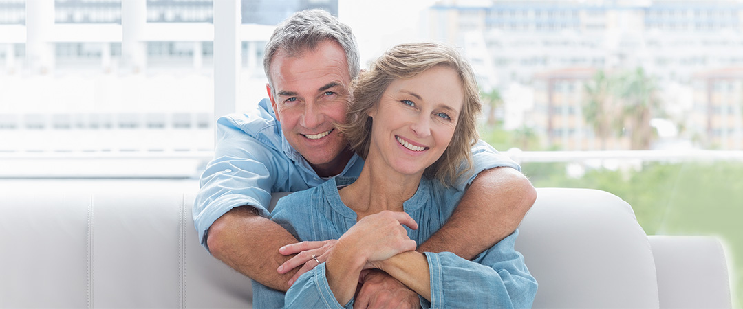 Senior couple in blue shirts with their arms around each other.